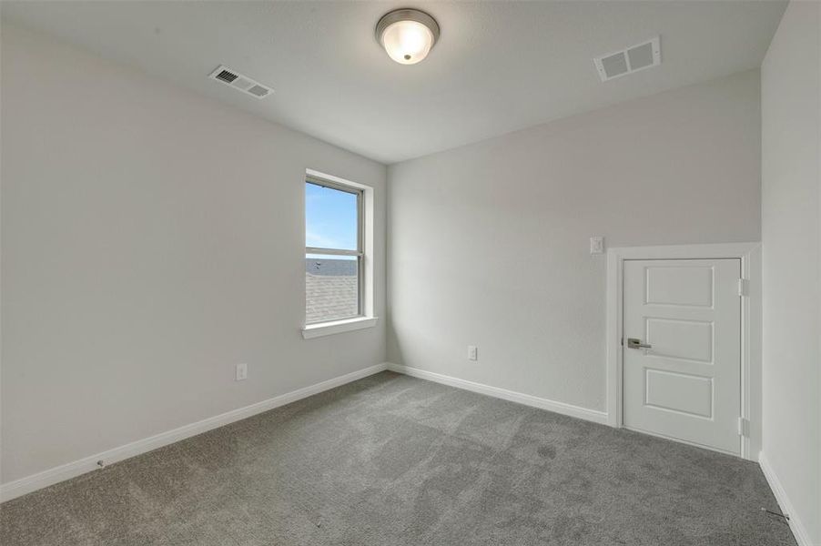 Carpeted room with a single window and a white paneled door