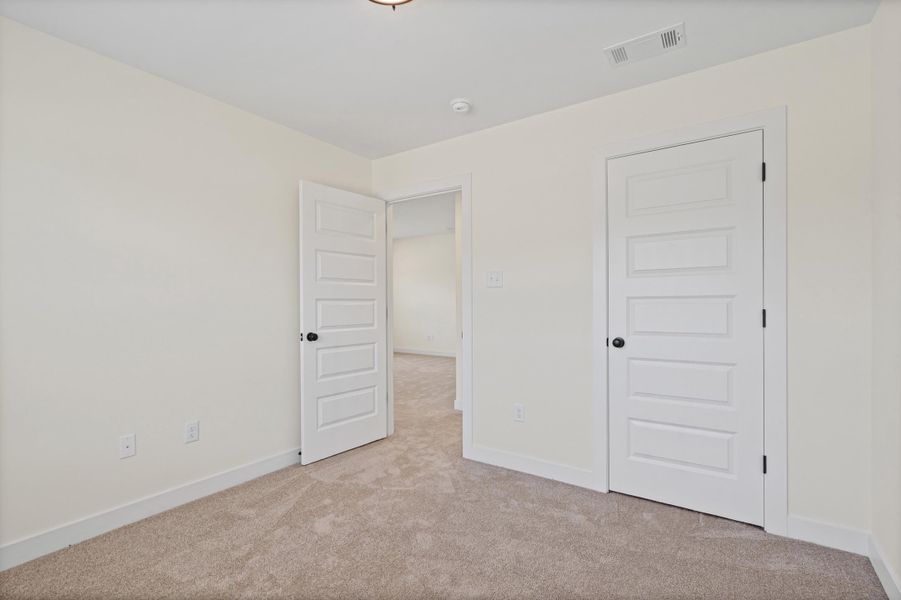 Neutral-toned room featuring a light beige carpet and white baseboards Neutral-toned room featuring a light beige carpet and white baseboards