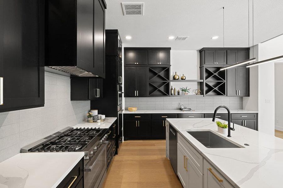 Above the built-in gas range a custom vent hood blends seamlessly with the stacked cabinetry.