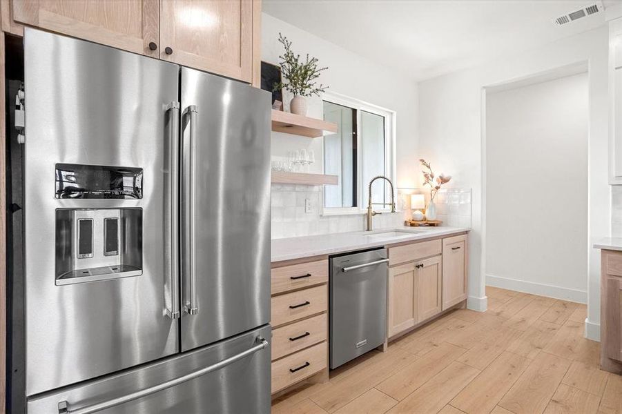 Kitchen featuring sink, light hardwood / wood-style flooring, light brown cabinetry, tasteful backsplash, and stainless steel appliances