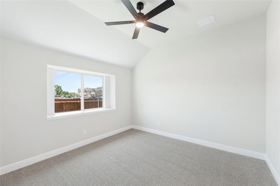 Empty bedroom with vaulted ceiling, black ceiling fan, carpet flooring, and a single window Empty bedroom with vaulted ceiling, black ceiling fan, carpet flooring, and a single window