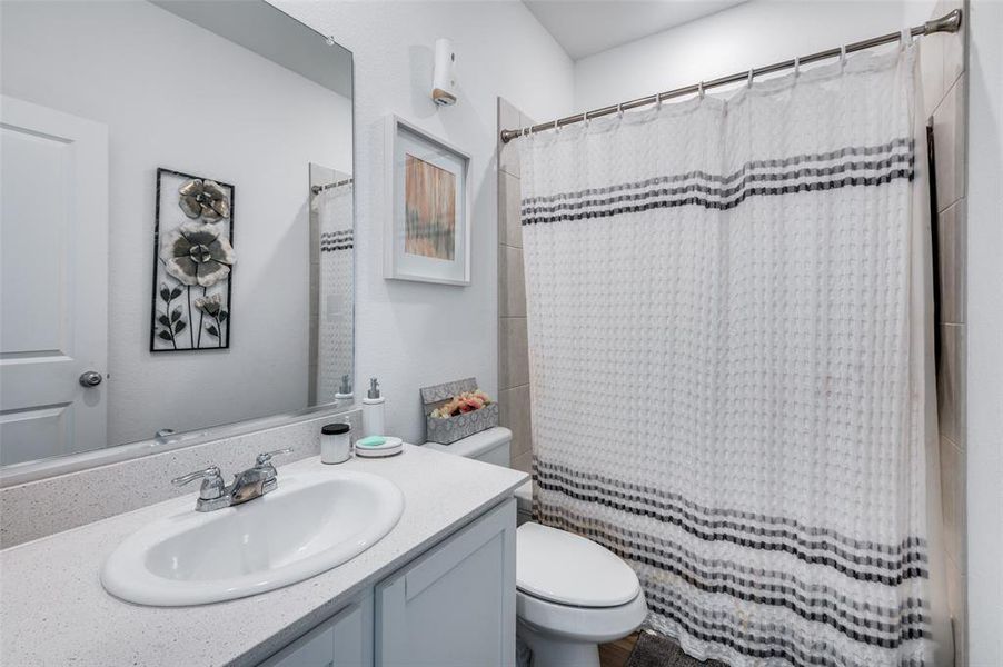 Bathroom featuring a shower with curtain, vanity, and toilet