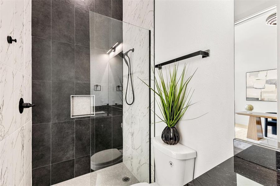 Contemporary shower enclosure featuring a clear glass panel, dark large-format wall tiles, white marble-look wall tiles, a built-in shower niche, and a contrasting hex tile shower floor