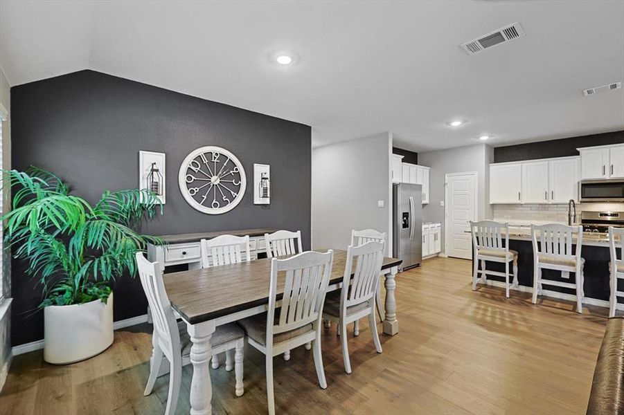 Dining space with lofted ceiling and light hardwood / wood-style flooring