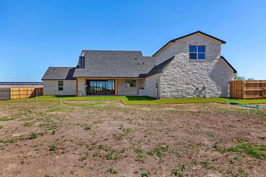 Back of house featuring a fenced backyard, a patio, and stone siding Back of house featuring a fenced backyard, a patio, and stone siding