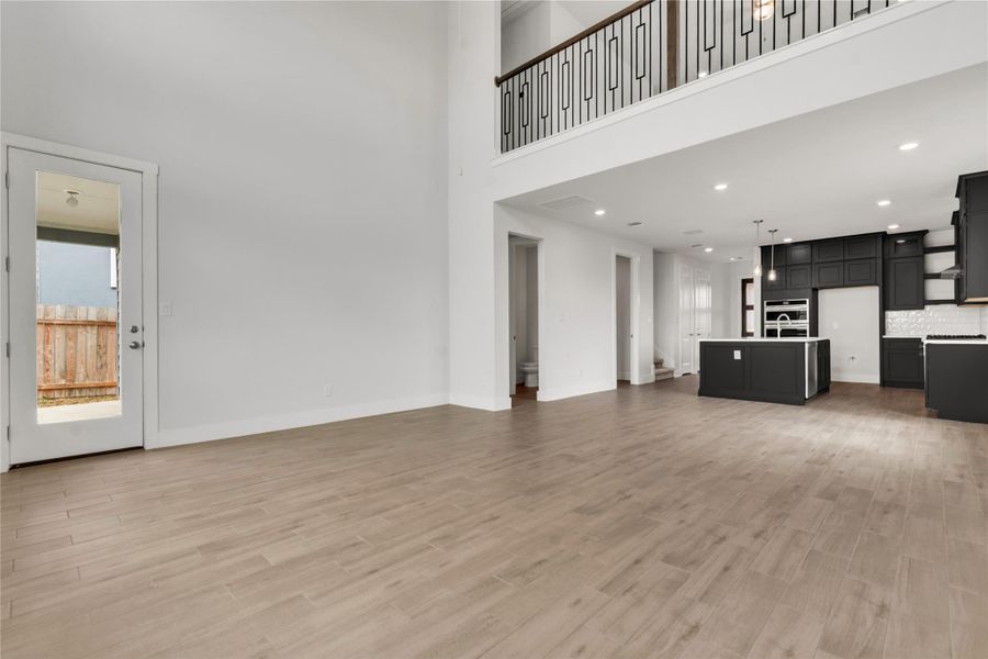 A grand, open-concept living space with lofty ceilings flows seamlessly into a modern, well-appointed kitchen.