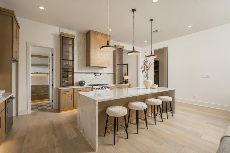 The kitchen’s generous scale and extended island seating create a true entertaining centerpiece, while the open layout maintains an effortless connection to the surrounding living spaces.
