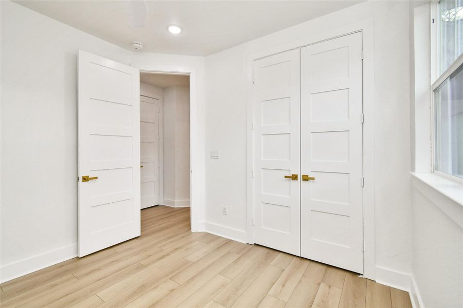This well-appointed bedroom showcases high-quality craftsmanship with five-panel shaker doors and elegant brushed gold hardware. The neutral palette and recessed lighting ensure a comfortable and inviting atmosphere.