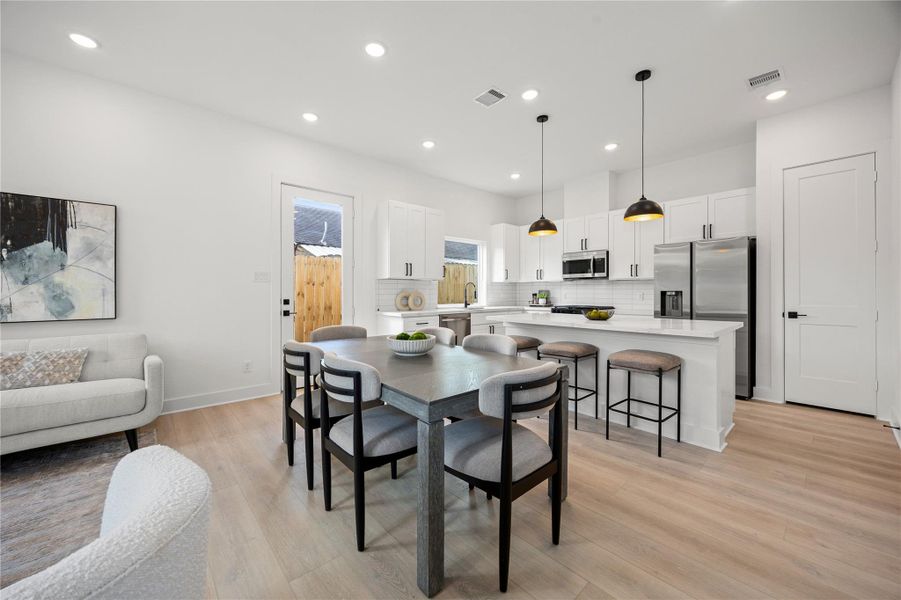 Start your day with a warm cup of coffee and quality time in this charming dining area! Highlights include high ceilings with recessed lighting, custom neutral paint, vinyl plank flooring, and a convenient door leading to the backyard. Start your day with a warm cup of coffee and quality time in this charming dining area! Highlights include high ceilings with recessed lighting, custom neutral paint, vinyl plank flooring, and a convenient door leading to the backyard.