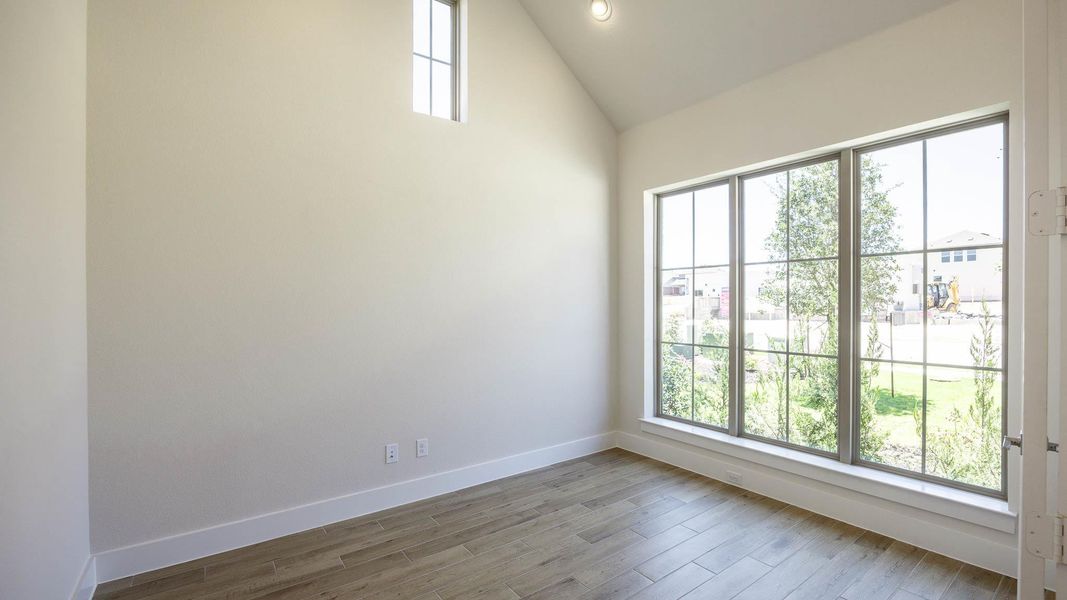 Unfurnished room with wood finished floors and vaulted ceiling Unfurnished room with wood finished floors and vaulted ceiling