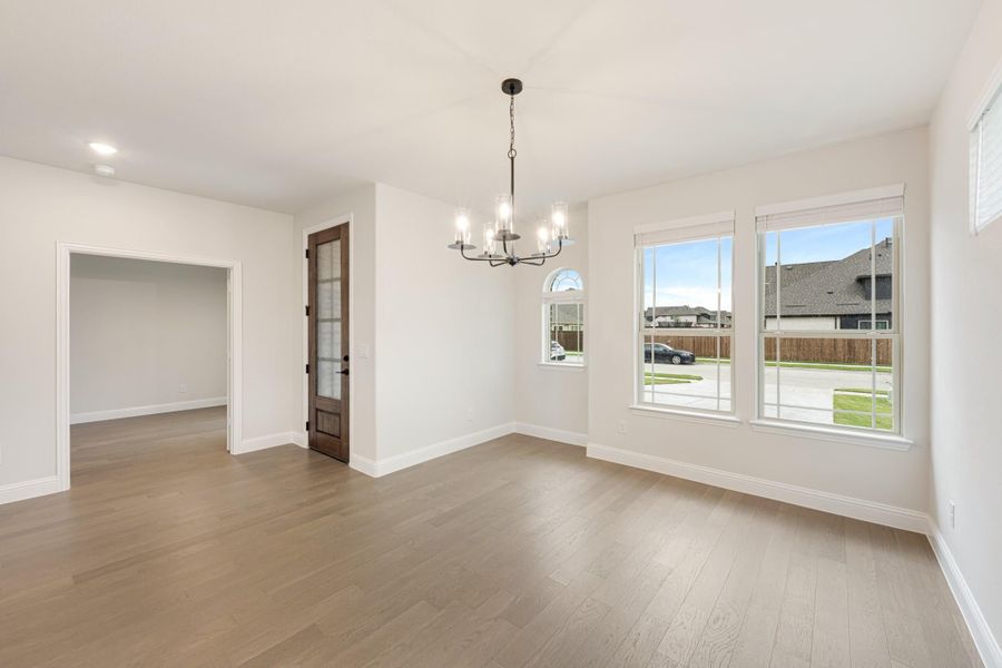 Empty dining room with hardwood floors, chandelier, and large windows overlooking the neighborhood Empty dining room with hardwood floors, chandelier, and large windows overlooking the neighborhood