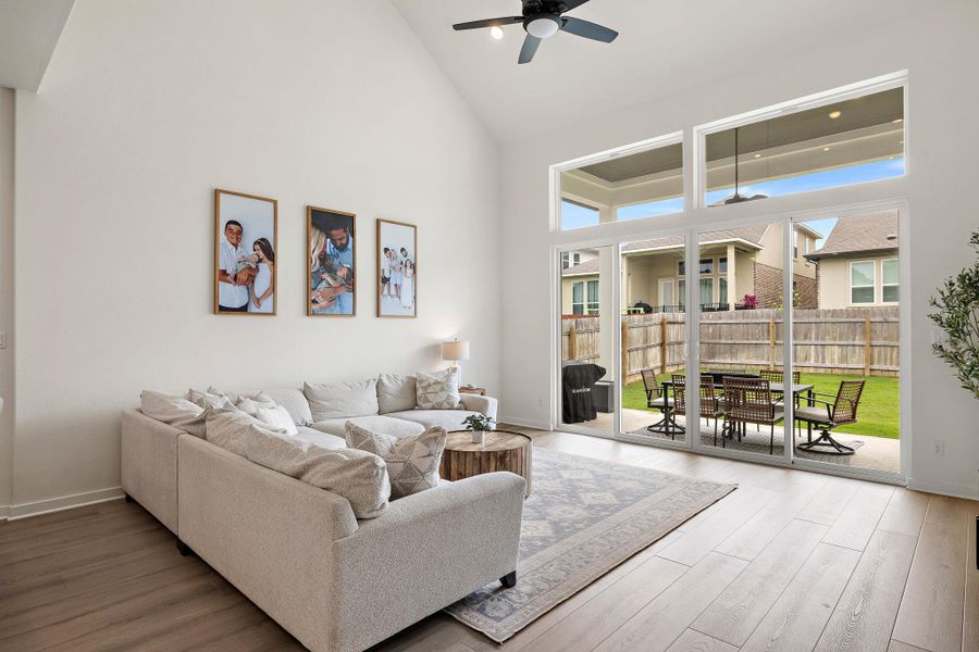 Vaulted ceiling living area featuring wood-finish flooring and a ceiling fan