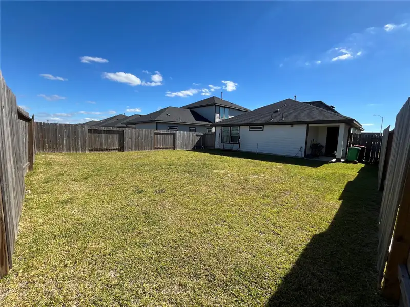 Spacious backyard with a well-maintained lawn, wooden fencing for privacy, and a view of neighboring houses. Ideal for outdoor activities or gardening.