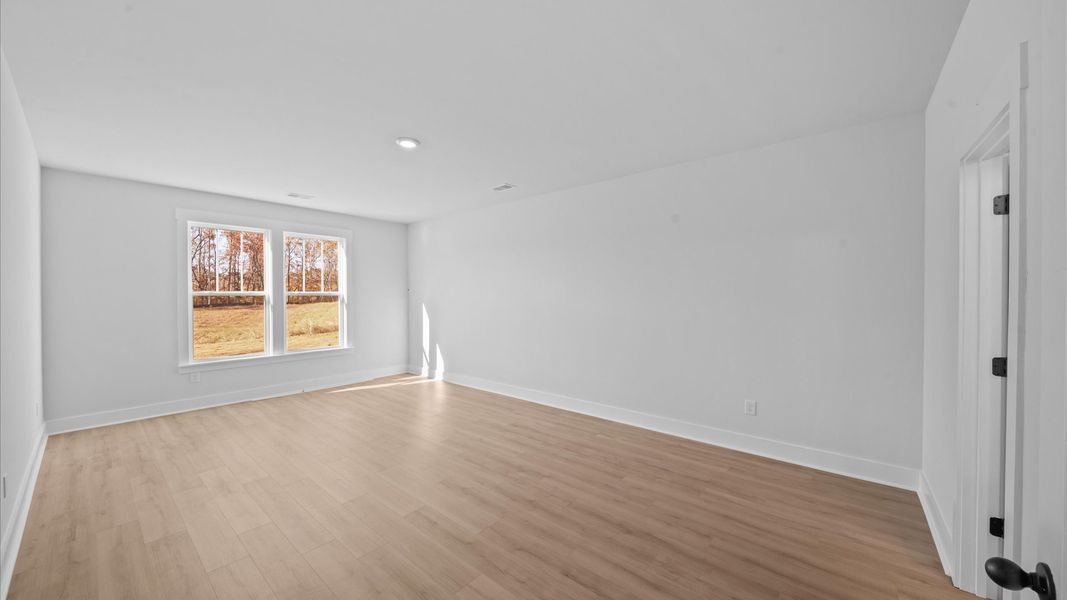Elegant primary suite with hardwood flooring and superior natural light in this accomplished DRB Homes design