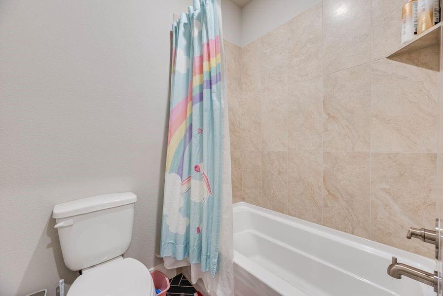 Bathroom with toilet and shower / bathtub combination with curtain