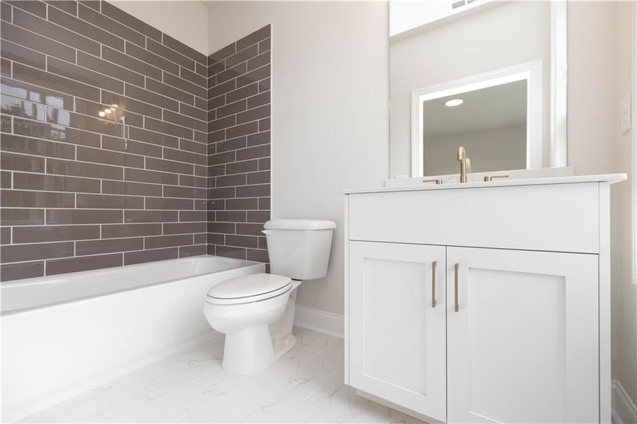 Full bathroom featuring tiled shower / bath, vanity, and toilet