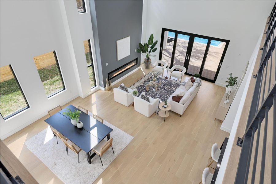 Living area with a high ceiling, a glass covered fireplace, and light wood-type flooring