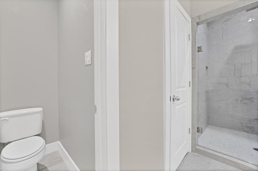 Bathroom featuring toilet and a shower with shower door