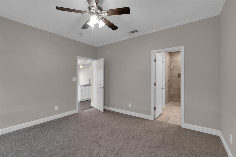 bedroom with ensuite bath, crown molding, ceiling fan, and light colored carpet