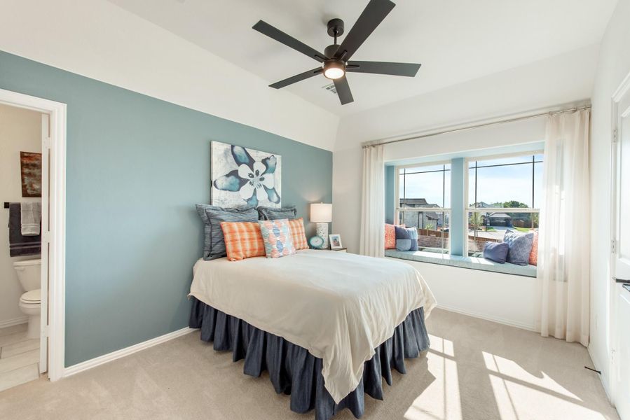 Bedroom with teal accent wall, ceiling fan, window seat, and ensuite bathroom door Bedroom with teal accent wall, ceiling fan, window seat, and ensuite bathroom door