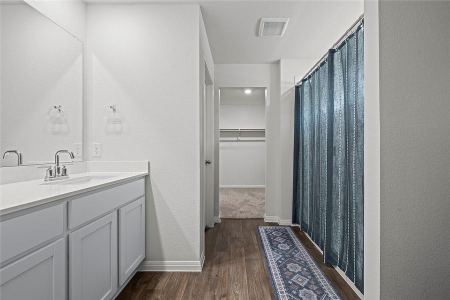 A clean and functional bathroom vanity, leading to a hallway with a carpeted closet.