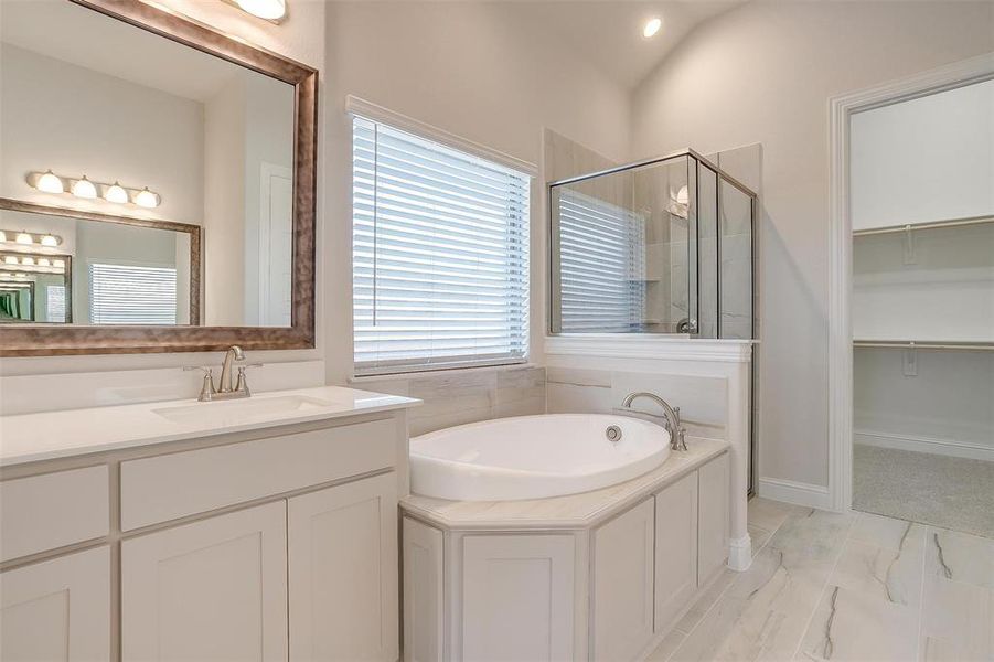 Bathroom featuring independent shower and bath, lofted ceiling, vanity, and tile patterned floors