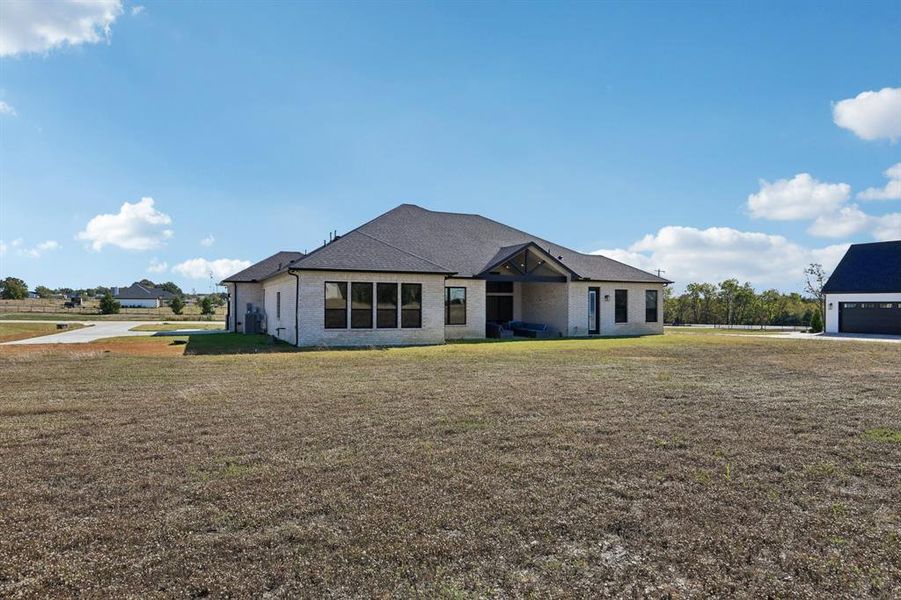 View of front of house with a front yard, brick siding, and a patio area View of front of house with a front yard, brick siding, and a patio area