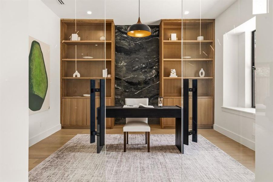 Dedicated office space featuring a built-in wood-finish shelving system, dark stone-finish accent wall, and wood-finish flooring