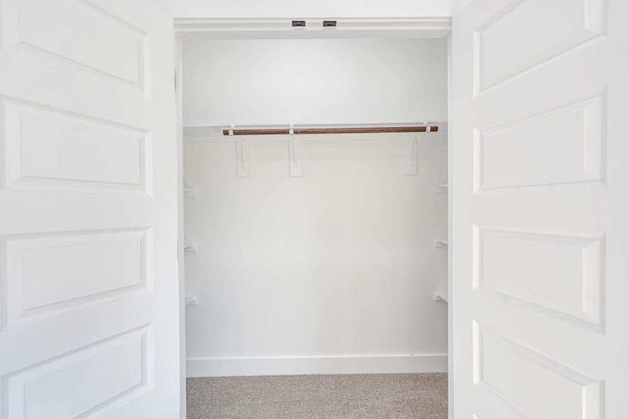 Second primary bedroom closet offering additional storage space with built-in hanging rod and shelving.
