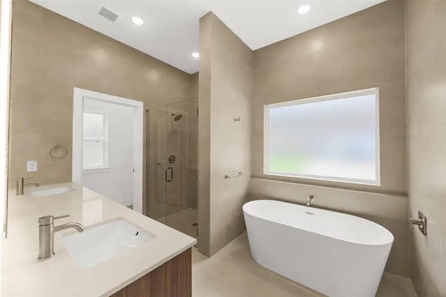 Spa-inspired bathroom featuring a freestanding soaking tub, oversized walk-in shower, and floor-to-ceiling tile.