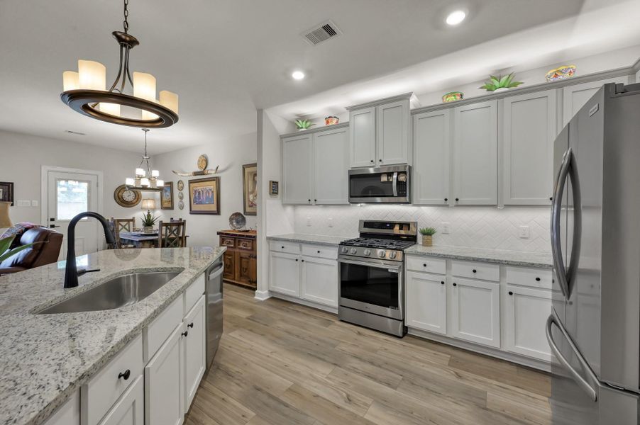 Bright, modern kitchen showcases granite countertops, an oversized island with undermount sink, stainless steel appliances, gas range, extensive cabinetry, and stylish finishes designed for both functionality and entertaining. Bright, modern kitchen showcases granite countertops, an oversized island with undermount sink, stainless steel appliances, gas range, extensive cabinetry, and stylish finishes designed for both functionality and entertaining.