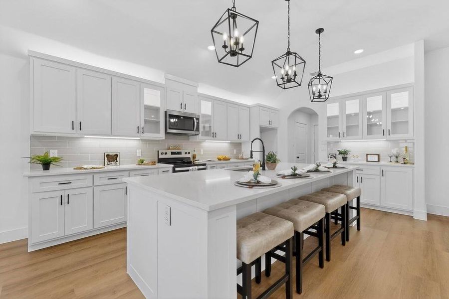 Kitchen featuring glass insert cabinets, arched walkways, a breakfast bar, white cabinetry, and electric range oven Kitchen featuring glass insert cabinets, arched walkways, a breakfast bar, white cabinetry, and electric range oven