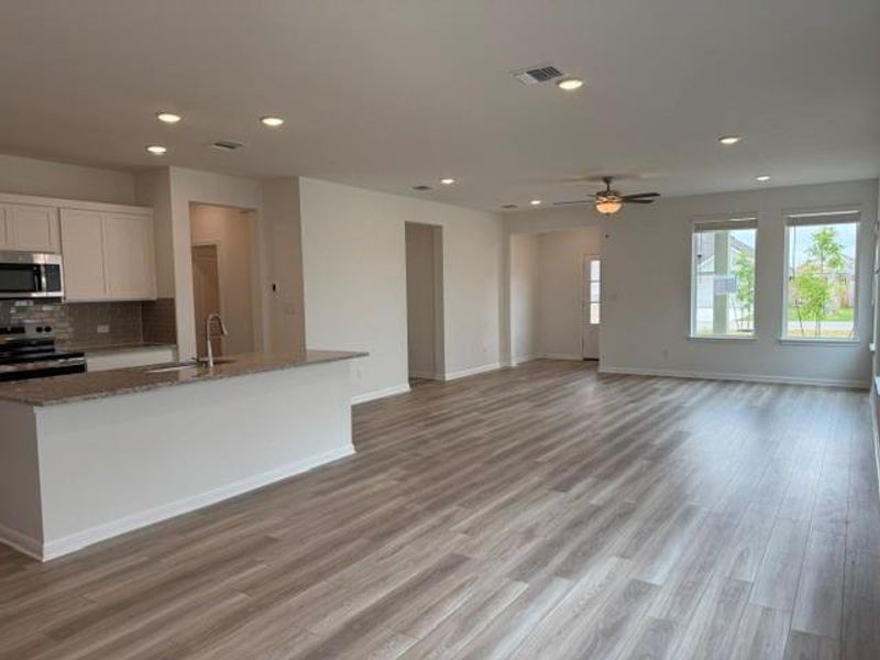Open-concept living space featuring wood-finish flooring, recessed lighting, and a contemporary ceiling fan