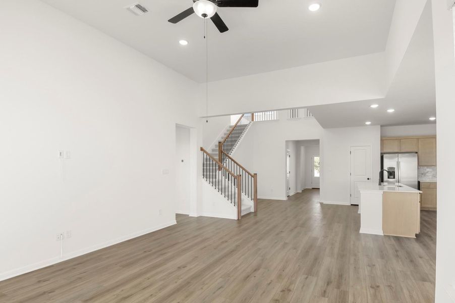 Unfurnished living room with recessed lighting, light wood-style floors, stairway, a towering ceiling, and ceiling fan
