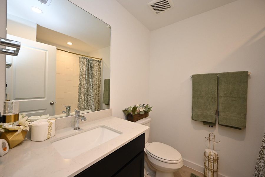 This modern bathroom features a sleek white countertop with a single sink, elegant fixtures, and a large mirror. It includes a shower/tub combo. This modern bathroom features a sleek white countertop with a single sink, elegant fixtures, and a large mirror. It includes a shower/tub combo.