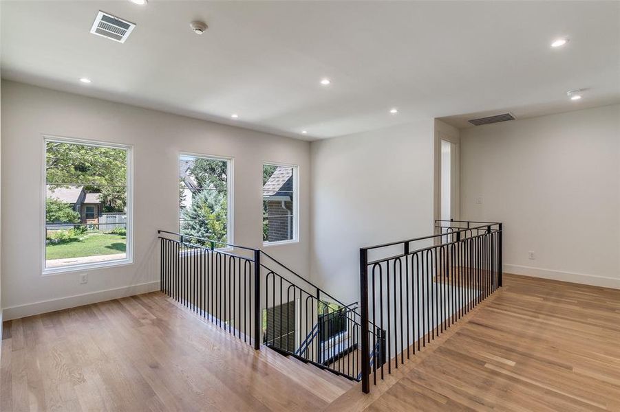 Corridor with recessed lighting, light wood-type flooring, and an upstairs landing Corridor with recessed lighting, light wood-type flooring, and an upstairs landing