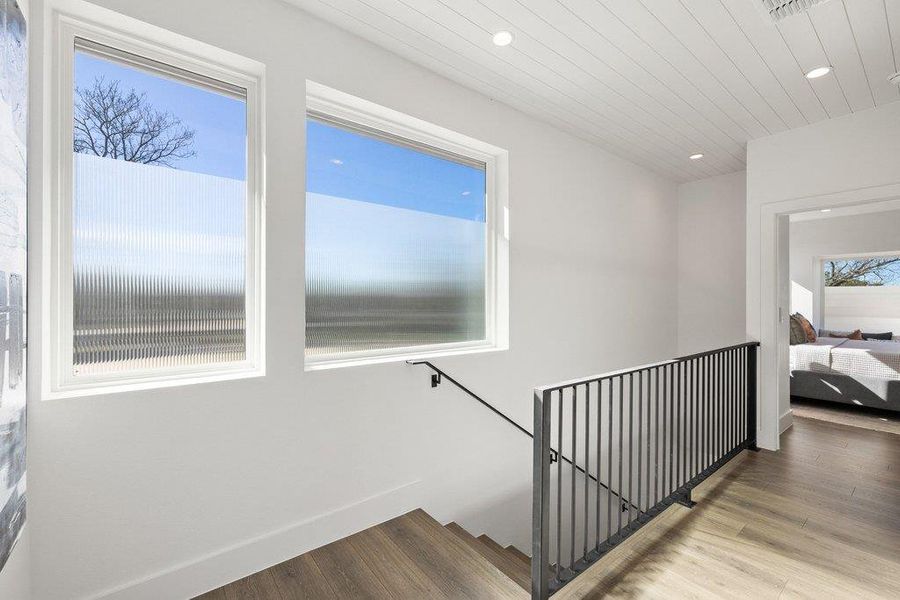 Custom steel stair rail, ship lap ceiling, large windows and landing at the top of the stairs