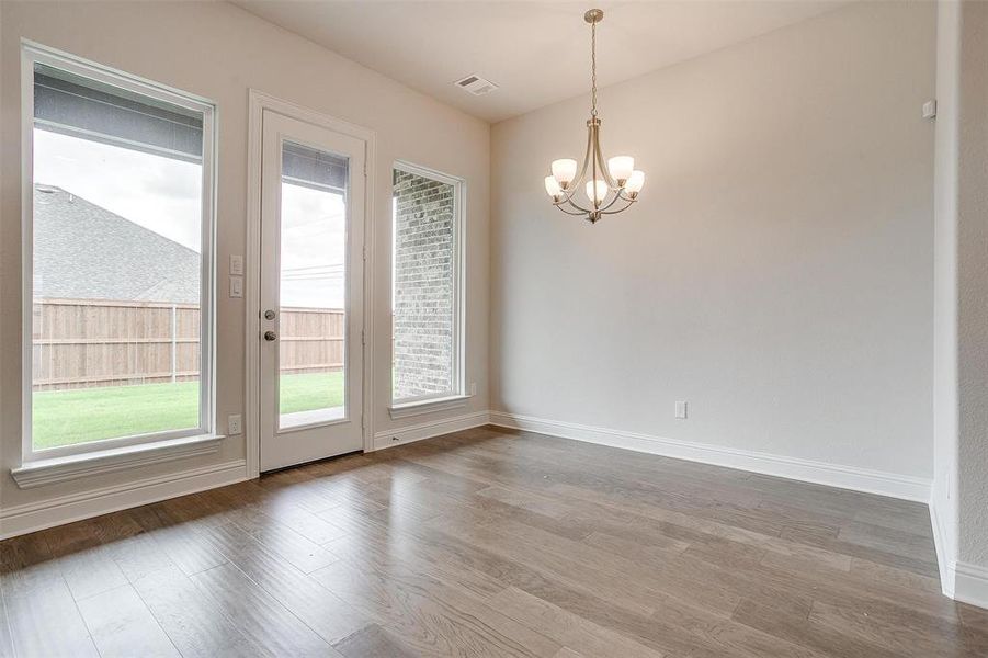 Unfurnished room featuring hardwood / wood-style floors and a notable chandelier