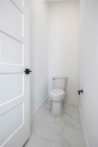 Bathroom featuring toilet and light marble finish floors