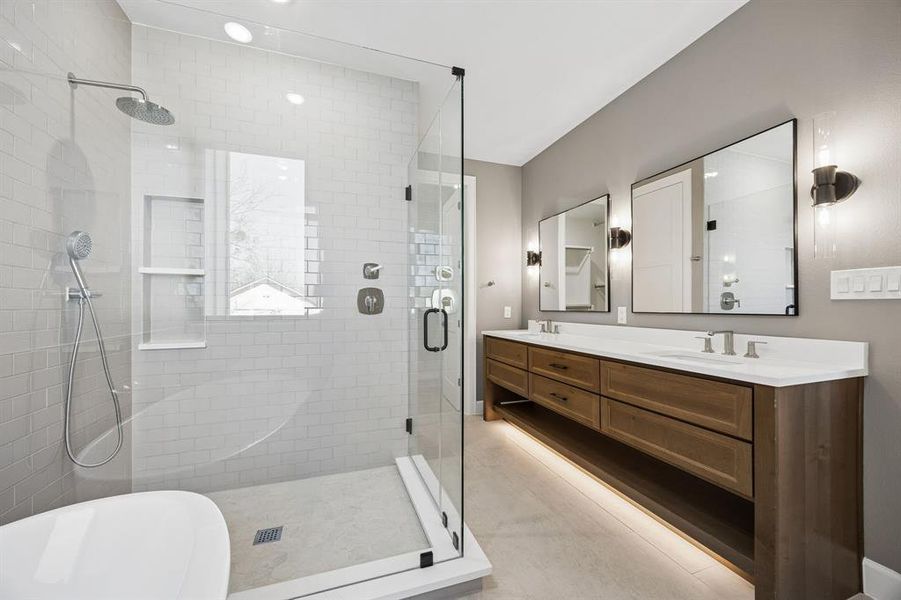 Bathroom featuring a freestanding tub, double vanity, a stall shower, light tile patterned flooring, and recessed lighting Bathroom featuring a freestanding tub, double vanity, a stall shower, light tile patterned flooring, and recessed lighting