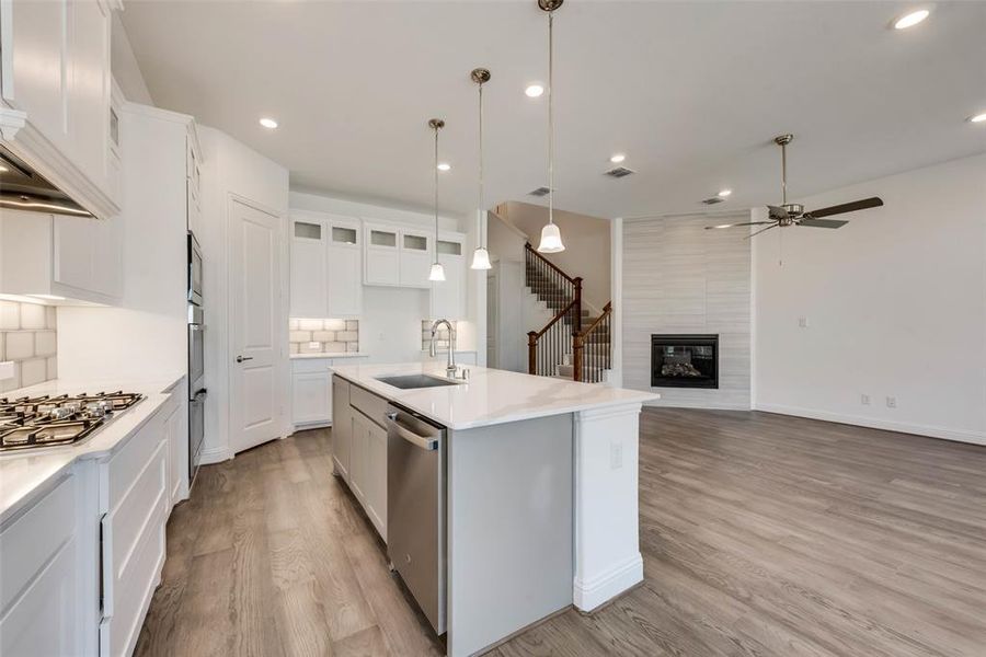 Kitchen featuring sink, light hardwood / wood-style flooring, white cabinetry, and a kitchen island with sink