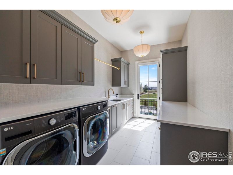 Main floor laundry with Milarc cabinetry, quartz countertops, large sink, and custom dog kennels opening up to the turf dog run