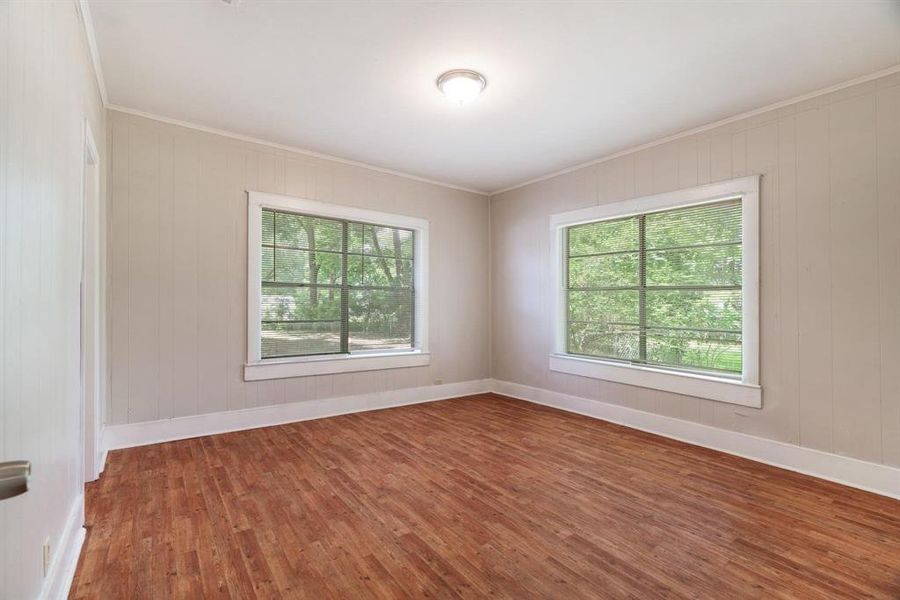 Unfurnished room with dark wood-style floors, crown molding, and wooden walls Unfurnished room with dark wood-style floors, crown molding, and wooden walls