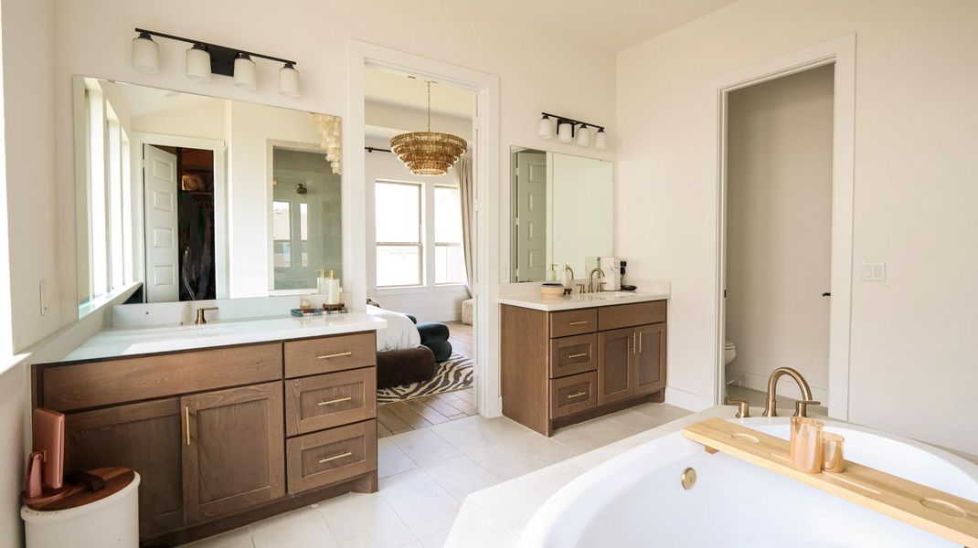Luxurious primary bathroom featuring dual vanities, a spacious soaking tub, and elegant tile flooring. Luxurious primary bathroom featuring dual vanities, a spacious soaking tub, and elegant tile flooring.