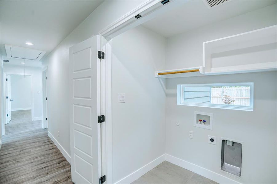 Dedicated laundry area with built-in shelving, hanging rod, and a horizontal window