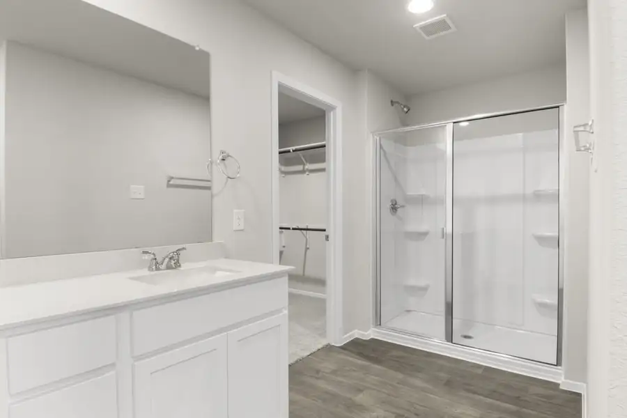 Image of primary bathroom with white cabinets and a standing shower