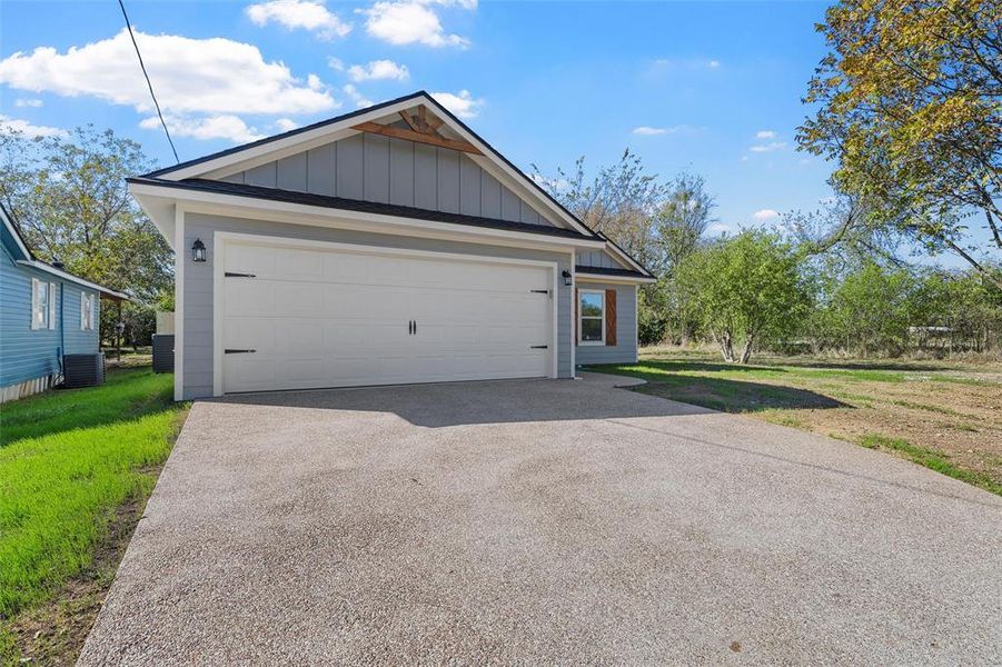 View of front of home with a garage, board and batten siding, a front yard, and driveway