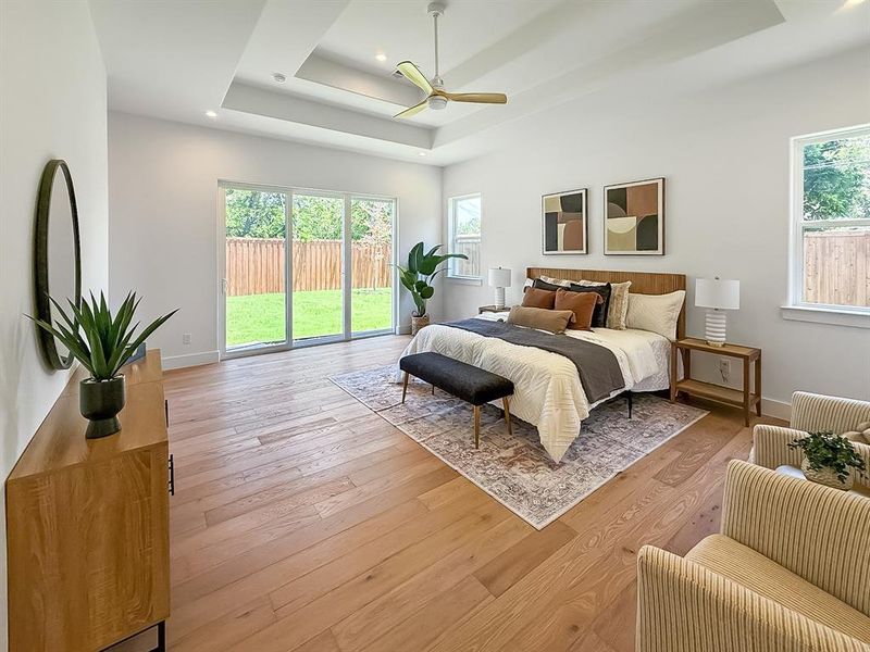 Bedroom featuring a tray ceiling, access to exterior, light wood-style flooring, a ceiling fan, and recessed lighting Bedroom featuring a tray ceiling, access to exterior, light wood-style flooring, a ceiling fan, and recessed lighting