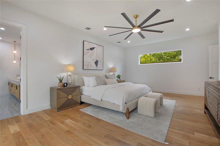 Bedroom with ensuite bath, light hardwood / wood-style flooring, and ceiling fan