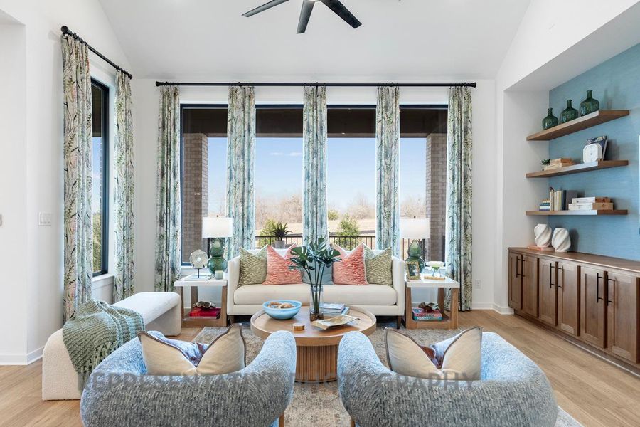 Living room with lofted ceiling, light wood-type flooring, and a ceiling fan